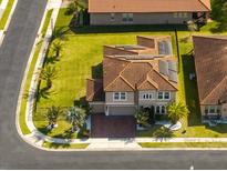 Stunning aerial view of home with red tiled roof, solar panels, and lush landscaping at 1720 Benoit Ter, Davenport, FL 33837