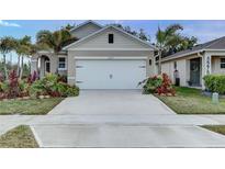 Inviting home exterior featuring a neutral color palette, an attached two-car garage and tropical landscaping at 2271 Delhi Pl, Sanford, FL 32771