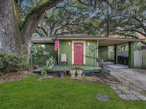 Charming green home featuring a welcoming front porch, red door, and a convenient carport at 2410 E Church St, Orlando, FL 32803