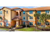 A vibrant multi-story condo building with a terra cotta roof, lush landscaping and welcoming entrance at 5483 Vineland Rd # 10103, Orlando, FL 32811