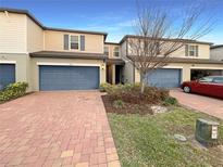 Townhome with blue garage doors, brick driveway, and landscaping at 987 Desert Candle Dr, Ocoee, FL 34761