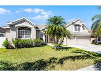 Inviting front yard featuring a well-maintained lawn, mature palm trees, and an attached two-car garage at 14136 Magnolia Glen Cir, Orlando, FL 32828
