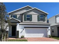 Charming two-story home featuring a two-car garage, gray siding and green shutters at 2000 Heart Lake Dr, Groveland, FL 34736