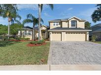 Charming home featuring a three-car garage, well-manicured lawn, and lush tropical landscaping at 2523 Water Valley Dr, St Cloud, FL 34771