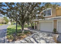 Charming condo exterior with attached garage and well-maintained landscaping, nestled beneath a beautiful mature tree at 2679 Metro Sevilla Dr # 101, Orlando, FL 32835