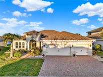 Beautiful single-story home with a tile roof, three-car garage and well manicured lawn and brick driveway at 3707 Paradiso Cir, Kissimmee, FL 34746