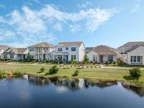 Beautiful exterior view of houses near a serene pond under a partly cloudy sky at 2970 Scout St, St Cloud, FL 34771