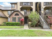 Charming condo exterior featuring brick accents, landscaped grounds, and convenient stairwell access to upper units at 320 Black Oak Ct # 102, Altamonte Springs, FL 32701