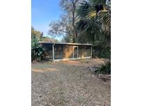 Exterior view of screened-in porch on sunny day with leafy yard at 450 Cassady St, Umatilla, FL 32784