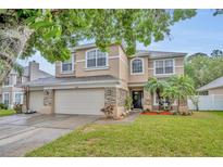 Charming two-story home with well-maintained lawn, stone accents, and a two-car garage at 13812 Magnolia Glen Cir, Orlando, FL 32828