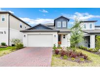 Charming home featuring a two-car garage, stylish blue accents, and a well-maintained front yard with greenery at 2313 Mystic Maze Ln, Clermont, FL 34715