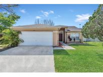 Charming single-story home featuring a two-car garage, manicured lawn, and inviting front entrance at 2421 Hybrid Dr, Kissimmee, FL 34758