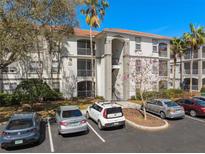 Condo exterior with stucco walls, a red tile roof, palm trees, and plenty of parking on a beautiful, sunny day at 2717 Maitland Crossing Way # 205, Orlando, FL 32810