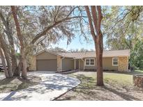 Charming single-story home featuring a well-manicured lawn, stone accents, and a curved driveway at 323 Marjorie Blvd, Longwood, FL 32750