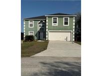 Two-story green home with clean white trim and a spacious two-car garage and driveway at 428 Ohio Ln, Kissimmee, FL 34759