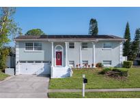 Inviting two-story home with a bright red front door, solar panels, well-kept lawn, and attached garage at 504 Teakwood Dr, Altamonte Springs, FL 32714