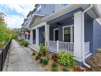 Inviting blue townhome with a covered porch, ceiling fan, and beautifully landscaped front yard at 1304 Spotted Sandpiper Loop, Winter Springs, FL 32708