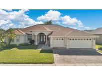 Inviting single story home showcasing a manicured lawn, mature landscaping, and a three car garage at 2509 Chapala Dr, Kissimmee, FL 34746