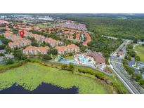 Aerial view of resort-style community with pool, waterslides and lush landscaping near a pond and surrounding trees at 2774 Almaton Loop # 101, Kissimmee, FL 34747