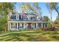 Charming two-story home with a brick chimney, dormers, and a well-manicured lawn and a patriotic flag at 7279 Nena Ct, Mount Dora, FL 32757