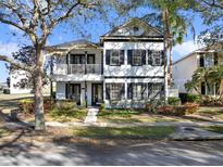 Charming two-story home with black and white trim, mature trees, and well-manicured landscaping at 7548 Gathering Dr, Reunion, FL 34747