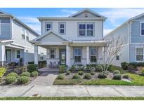 Charming two-story home with landscaped front yard and inviting covered porch with seating at 14317 Lanikai Beach Dr, Orlando, FL 32827