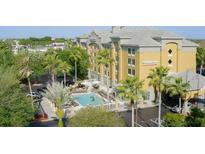 Resort exterior showing palm trees, swimming pool with lounge chairs and tables with umbrellas at 3000 Maingate Ln # 520, Kissimmee, FL 34747