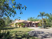 Stunning single-story home featuring a tile roof, brick accents, and a circular driveway surrounded by lush landscaping at 3150 Appaloosa Ct, Kissimmee, FL 34746