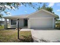 Charming single-story home with a two-car garage, manicured lawn, and inviting curb appeal at 328 Woodland Trl, Lady Lake, FL 32159