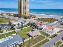 Gorgeous aerial view of a beach house with a spacious fenced yard, pool, and nearby ocean access at 385 Woodland Ave, Daytona Beach, FL 32118