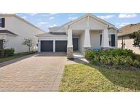 Charming home featuring a two-car garage, a well-maintained yard, and stone pillar details on the front porch at 4439 Davos Dr, Clermont, FL 34711