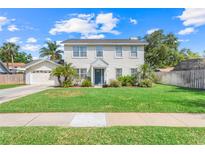 Charming two-story home featuring lush green lawn, freshly landscaped yard, and an attached two-car garage at 4451 Seawater Street, Orlando, FL 32812