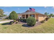 Charming home with well-maintained landscaping, green lawn, and visible American flag on a sunny day at 9491 Sw 98Th Ct, Ocala, FL 34481