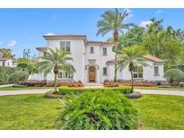 Beautiful two-story home featuring a red tile roof, white stucco and meticulously landscaped front yard with tropical palm trees at 1630 Lasbury Ave, Winter Park, FL 32789