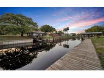 Waterfront home with dock, covered boat lift, and calm canal views under a beautiful dusk sky at 2072 Starboard Dr, Geneva, FL 32732