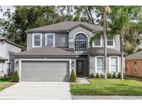 Charming two-story home featuring a gray exterior, two-car garage, and well-manicured lawn with palm trees at 2217 Wekiva Reserve Blvd, Apopka, FL 32703