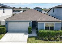 Charming single-story home features a two-car garage and manicured front lawn with lush landscaping at 297 Citrus Isle Loop, Davenport, FL 33837