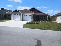 Inviting home with a well-manicured lawn, lush landscaping, and a two-car garage, offering great curb appeal at 5430 Samuel St, The Villages, FL 32163