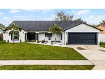 Charming single story home with a beautifully landscaped front yard, dark trim, and a 2-car garage at 645 Riverwoods Cir, Orlando, FL 32825