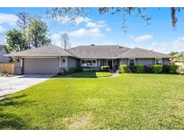 Beautifully landscaped front yard of a gray one-story home with a well-manicured green lawn at 8992 Palos Verde Dr, Orlando, FL 32825