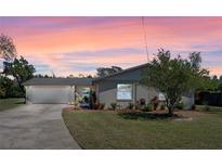 Charming single-story home with a well-manicured lawn and a freshly painted exterior at sunset at 1021 Mare Bello Dr, Winter Park, FL 32792