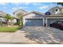 Two-car garage with blue door, driveway, and gray exterior paint offer ample parking and curb appeal at 1247 Travertine Ter, Sanford, FL 32771