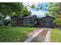 Charming single-story home features dark siding, manicured lawn, and a brick driveway, exuding curb appeal at 1432 W Yale St, Orlando, FL 32804