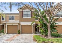 Charming two-story townhome featuring a tan stucco exterior, attached garage, and mature landscaping for added curb appeal at 2864 Polana St # 104, Orlando, FL 32835