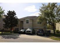 Inviting two-story home with a well-manicured lawn, three cars parked in the driveway, and mature trees offering shade at 3334 Fawnwood Dr, Ocoee, FL 34761