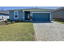 Charming single-story home with a blue exterior, well-maintained lawn, and a brick paver driveway at 434 Alcove Dr, Groveland, FL 34736