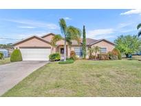 Charming single Gathering home with a two-car garage and beautiful landscaping with green grass and palm trees at 789 Kangaroo Ct, Deltona, FL 32738