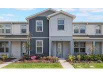 Charming townhome featuring two-tone gray exterior, landscaped lawn, and inviting front entrance at 9732 Brown Burrow St, Orlando, FL 32829