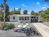 Welcoming curb appeal with rock landscaping, a colorful exterior, and a charming patio seating area on a sunny day at 134 Roberta Rd, Ormond Beach, FL 32176