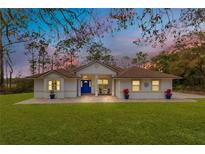 Charming single-story home featuring a manicured lawn and a striking blue front door at 30041 Redoak Ave, Eustis, FL 32736
